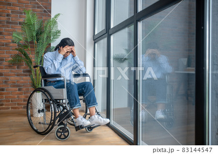 A young girl on a wheelchair looking frustrated and upset 83144547