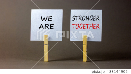Wooden clothespins with white sheets of paper. Text 'we are stronger together'. Beautiful gray background. Business concept, copy space. 83144902