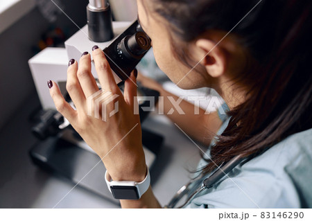 Scientist looks into microscope researching material sample at table in laboratory Scientist looks into microscope researching material sample at table in laboratory 83146290