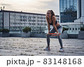 Young athletic woman smiling while doing squats exercises with sports rubber at the urban city location 83148168