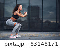 Young athletic woman doing squats exercises with sports rubber at the urban city location 83148171