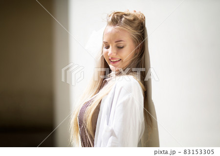 Portrait of young beautiful woman blonde hair standing against wall with copy space Portrait of young beautiful woman blonde hair standing against wall with copy space 83153305