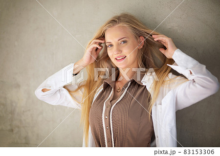 Portrait of young beautiful woman blonde hair standing against wall with copy space Portrait of young beautiful woman blonde hair standing against wall with copy space 83153306