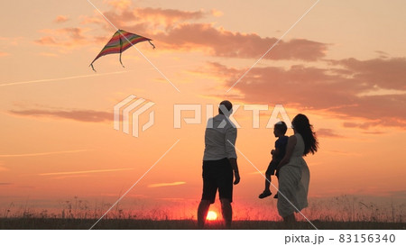 Happy family day, father mother and little kid fly a kite into the sky at sunset, play with child in nature in the evening, love spending time with family, raising and developing baby, cheerful life. Happy family day, father mother and little kid fly a kite into the sky at sunset, play with child in nature in the evening, love spending time with family, raising and developing baby, cheerful life. 83156340