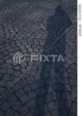 石畳に伸びた、写真撮影する人の長い影 83156495