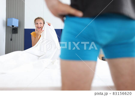 Woman sitting on bed looks at man in shorts closeup Woman sitting on bed looks at man in shorts closeup 83156620