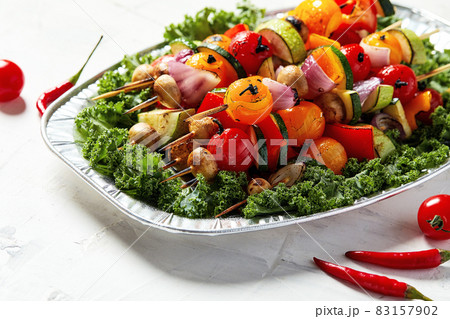 vegetarian skewers with dry herbs on wooden skewers of zucchini tomato onion mushrooms on a plate 83157902