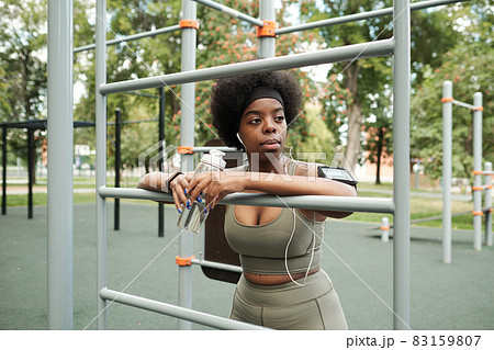 Young restful sportswoman listening to music in earphones 83159807