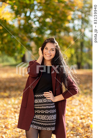 Portrait of a joyful young woman enjoying in the autumn park. 83159940