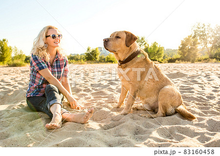 Young woman with her dog at the beach Young woman with her dog at the beach 83160458