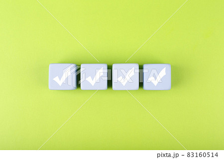Four checkmarks on white cubes against bright green background  83160514