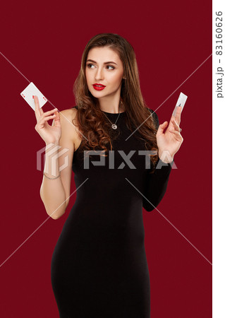 Beautiful caucasian woman in black dress with poker cards gambling in casino 83160626