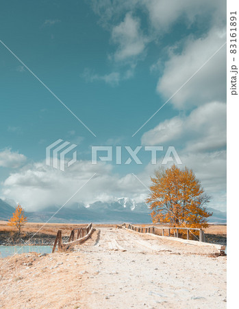 Old bridge across the river. Snowy mountains in the background. Old bridge across the river. Snowy mountains in the background. 83161891