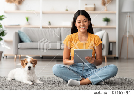 Pretty chinese woman watching pet owner blog on digital tablet 83165594