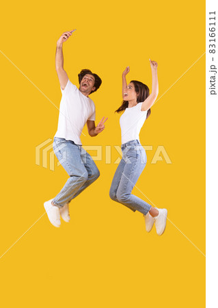 Excited millennial couple taking selfie and jumping at studio Excited millennial couple taking selfie and jumping at studio 83166111