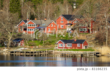 Picturesque summer houses painted in traditional falun red on dwellings island of the Stockholm archipelago in the Baltic Sea in the early morning. 83166235