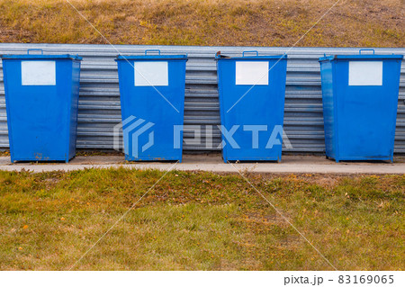Metal garbage cans of blue color stand on a special area in the open air on a summer day. Waste Metal garbage cans of blue color stand on a special area in the open air on a summer day. Waste 83169065