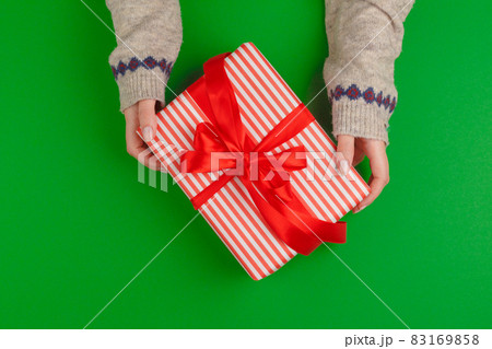Woman hands holding gift box on green background 83169858