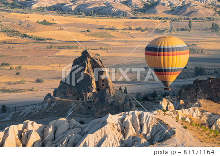 hot air balloon with rainbow colors pattern rising over the Cappadocian valley hot air balloon with rainbow colors pattern rising over the Cappadocian valley 83171164