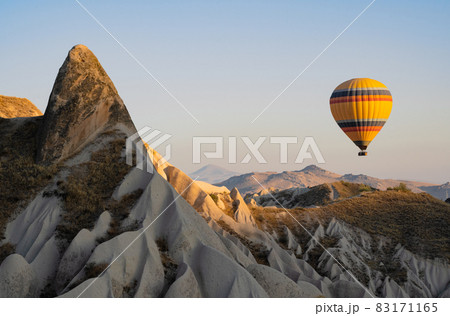 hot air balloon with rainbow colors pattern rising over the Cappadocian valley hot air balloon with rainbow colors pattern rising over the Cappadocian valley 83171165