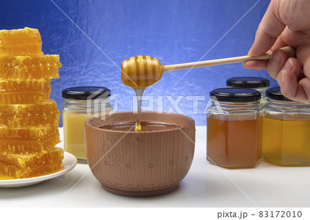fresh honey dripping from a spoon into a plate on a blue background. organic vitamin health food fresh honey dripping from a spoon into a plate on a blue background. organic vitamin health food 83172010