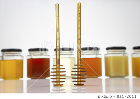 Hexagonal jars with different types and colors of fresh flower honey and a honey spoon. Hexagonal jars with different types and colors of fresh flower honey and a honey spoon. 83172011