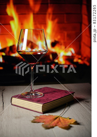 Dry Glass Of Red Wine on Book and Fireplace 83172265