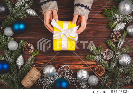 View from above of woman wearing sweater and holding a decorated present View from above of woman wearing sweater and holding a decorated present 83172882