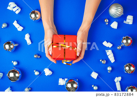 Female hands with gift box on a blue background Female hands with gift box on a blue background 83172884