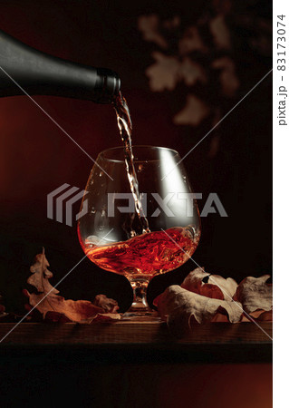 Brandy is poured from a bottle into a glass. Brandy is poured from a bottle into a glass. 83173074