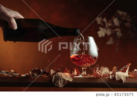 Brandy is poured from a bottle into a glass. 83173075