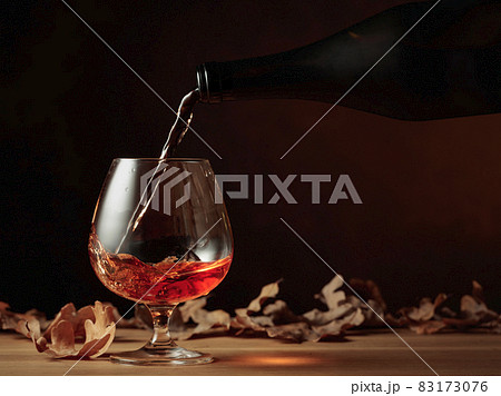 Brandy is poured from a bottle into a glass. Brandy is poured from a bottle into a glass. 83173076