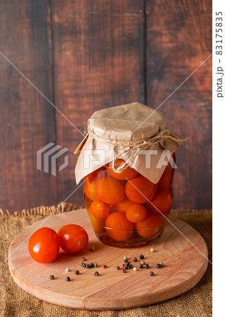 Pickled tomatoes in a glass jar on wooden background. Fermented trending food. Home rustic style. Pickled tomatoes in a glass jar on wooden background. Fermented trending food. Home rustic style. 83175835