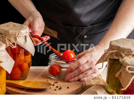 Woman ferments vegetables. Pickled tomatoes in jars. Preserving the autumn harvest. Organic food. Woman ferments vegetables. Pickled tomatoes in jars. Preserving the autumn harvest. Organic food. 83175836