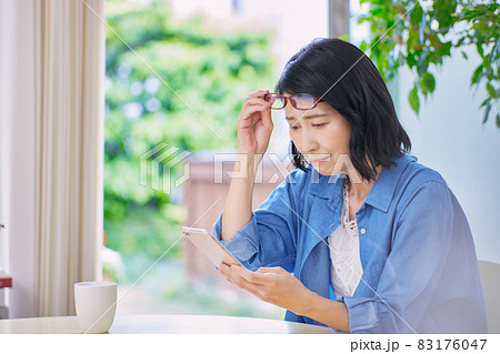 老眼でスマホが見えにくいミドル女性 83176047