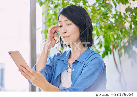 老眼でスマホが見えにくいミドル女性 老眼でスマホが見えにくいミドル女性 83176054