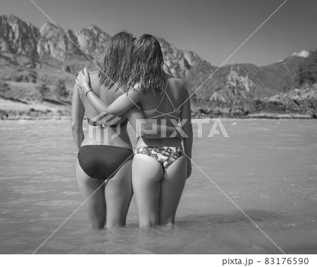 Two girls stay in river on mountains background 83176590