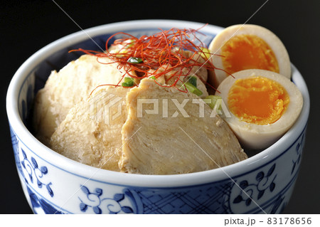 煮玉子と万能葱と糸切り唐辛子が乗っている鶏チャーシュー丼を黒背景で撮影 83178656