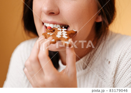 Close-up of teeth biting off freshly baked gingerbread cookie. Close-up of teeth biting off freshly baked gingerbread cookie. 83179046