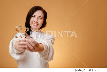 Woman on a yellow background holds a metal baking dish in her hands. Woman on a yellow background holds a metal baking dish in her hands. 83179666