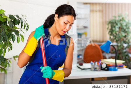 Woman wiping office floor with mop 83181171