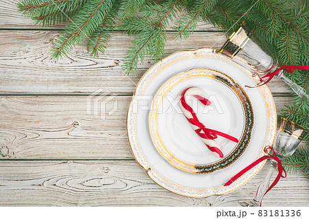 Wooden table with pine tree branches and holiday table setting Wooden table with pine tree branches and holiday table setting 83181336