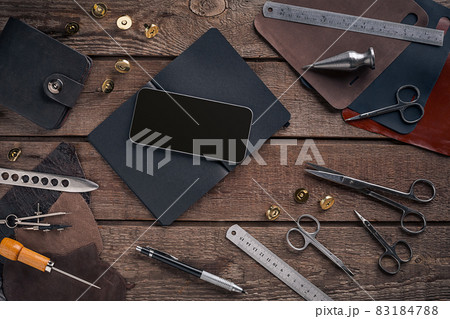 Leather craft or leather working. Leather working tools and cut out pieces of leather on work desk . 83184788