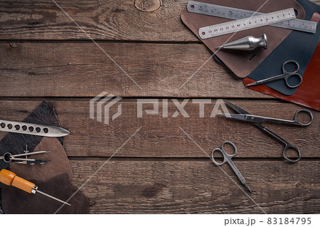 Leather craft or leather working. Leather working tools and cut out pieces of leather on work desk . 83184795