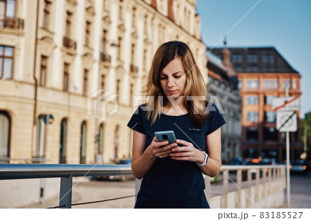 Woman using smartphone at city street Woman using smartphone at city street 83185527