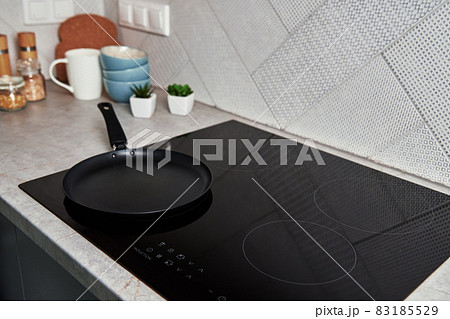Induction stove with cooking pan on it. Modern kitchen appliance Induction stove with cooking pan on it. Modern kitchen appliance 83185529