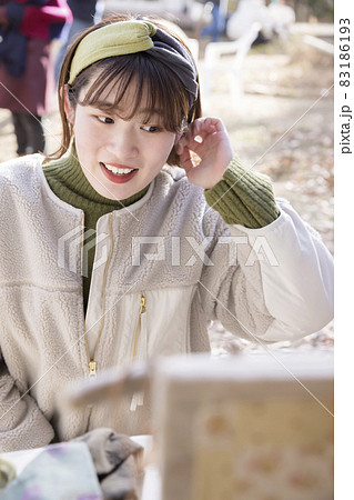 イベント出店のお店でヘアバンドを試着する若い女性　マルシェイメージ 83186193