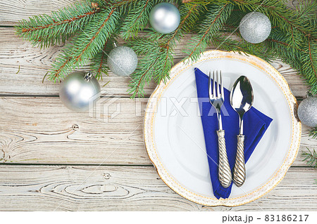 Wooden table with pine tree branches and holiday table setting 83186217