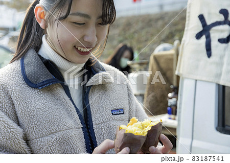 焼きたての焼き芋を半分に割る若い女性 焼きたての焼き芋を半分に割る若い女性 83187541