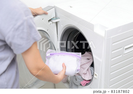 洗濯ネットに入れておしゃれ着洗いをする主婦の手元 83187802